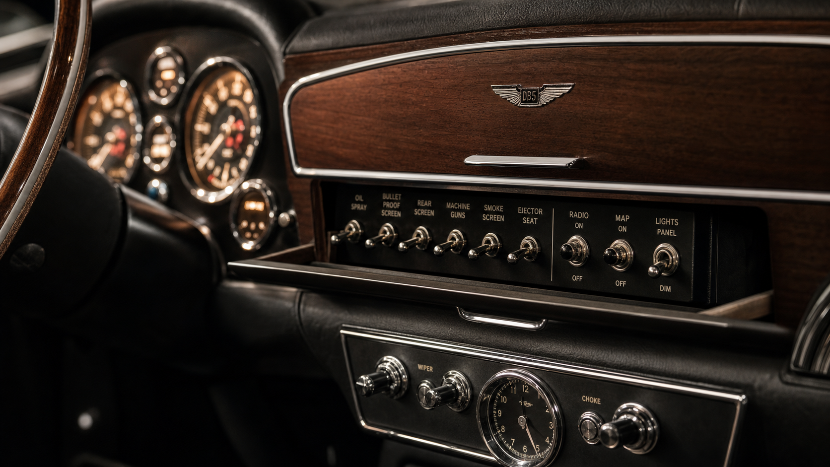 Close-up of a 1964 Aston Martin DB5 dashboard, hidden toggle switches revealed behind a sliding panel